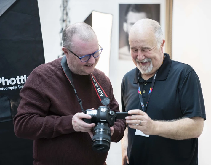 Two older students reviewing a photo on a DSLR camera screen in a professional studio setting. Two older students reviewing a photo on a DSLR camera screen in a professional studio setting.